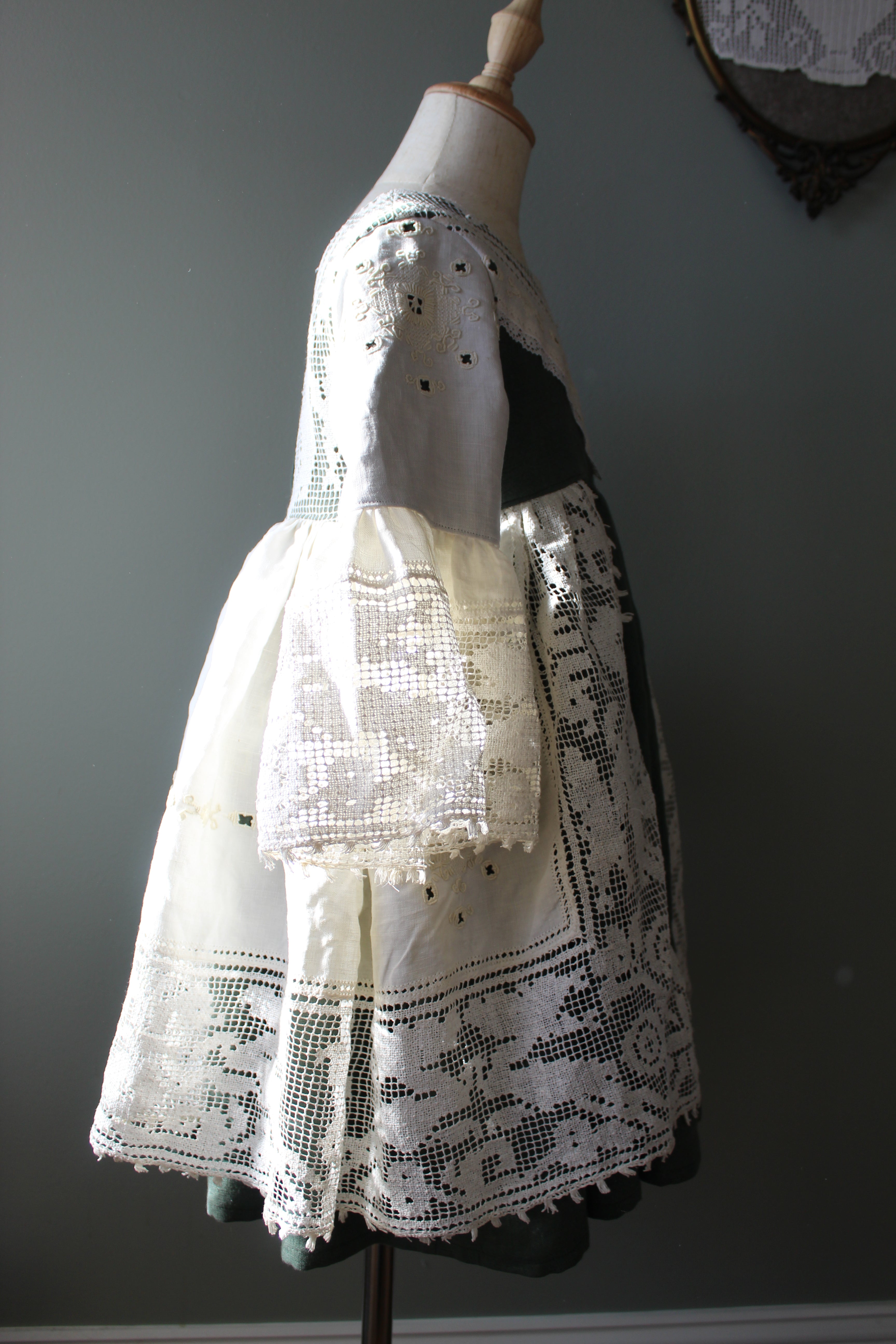 Mannequin wearing a white lace dress against a gray background