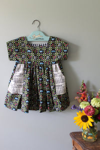 Floral-patterned tunic on a hanger with a bouquet of flowers on a light gray background