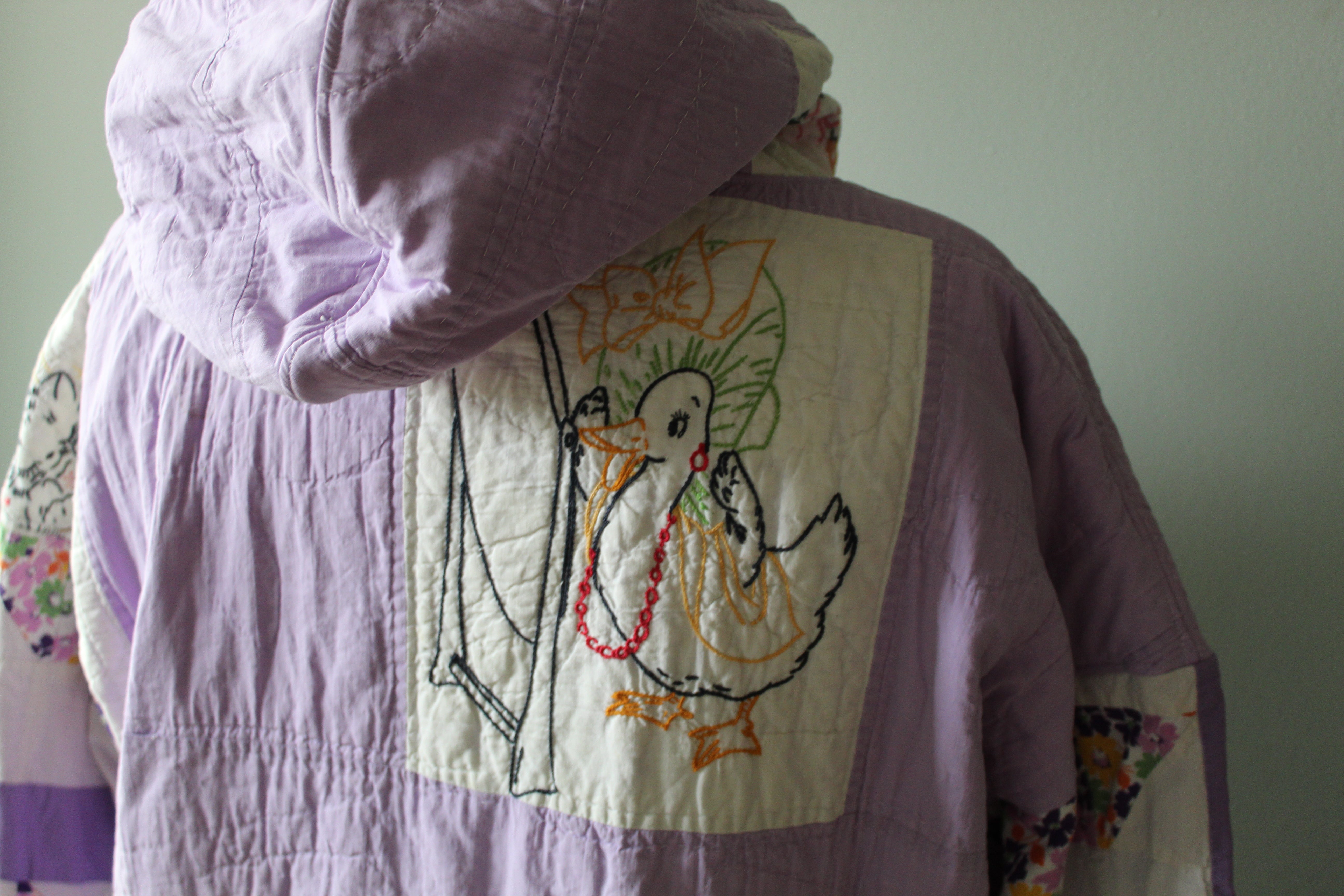 Purple quilt with embroidered duck design on a plain background