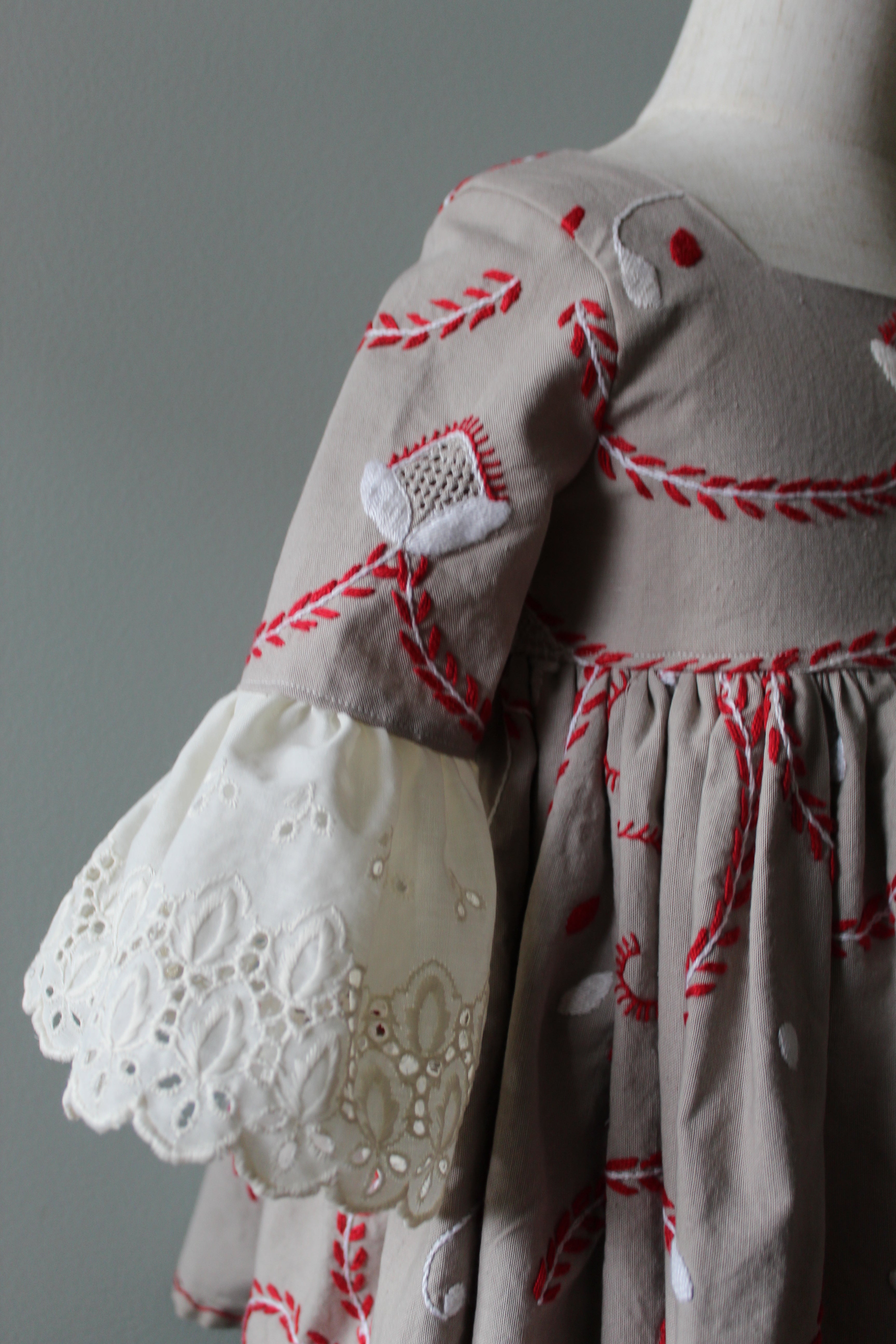 Close-up of a garment with red embroidery on a neutral background