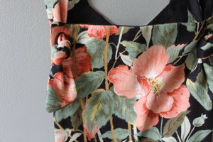Floral patterned fabric with pink flowers and green leaves on a black background.