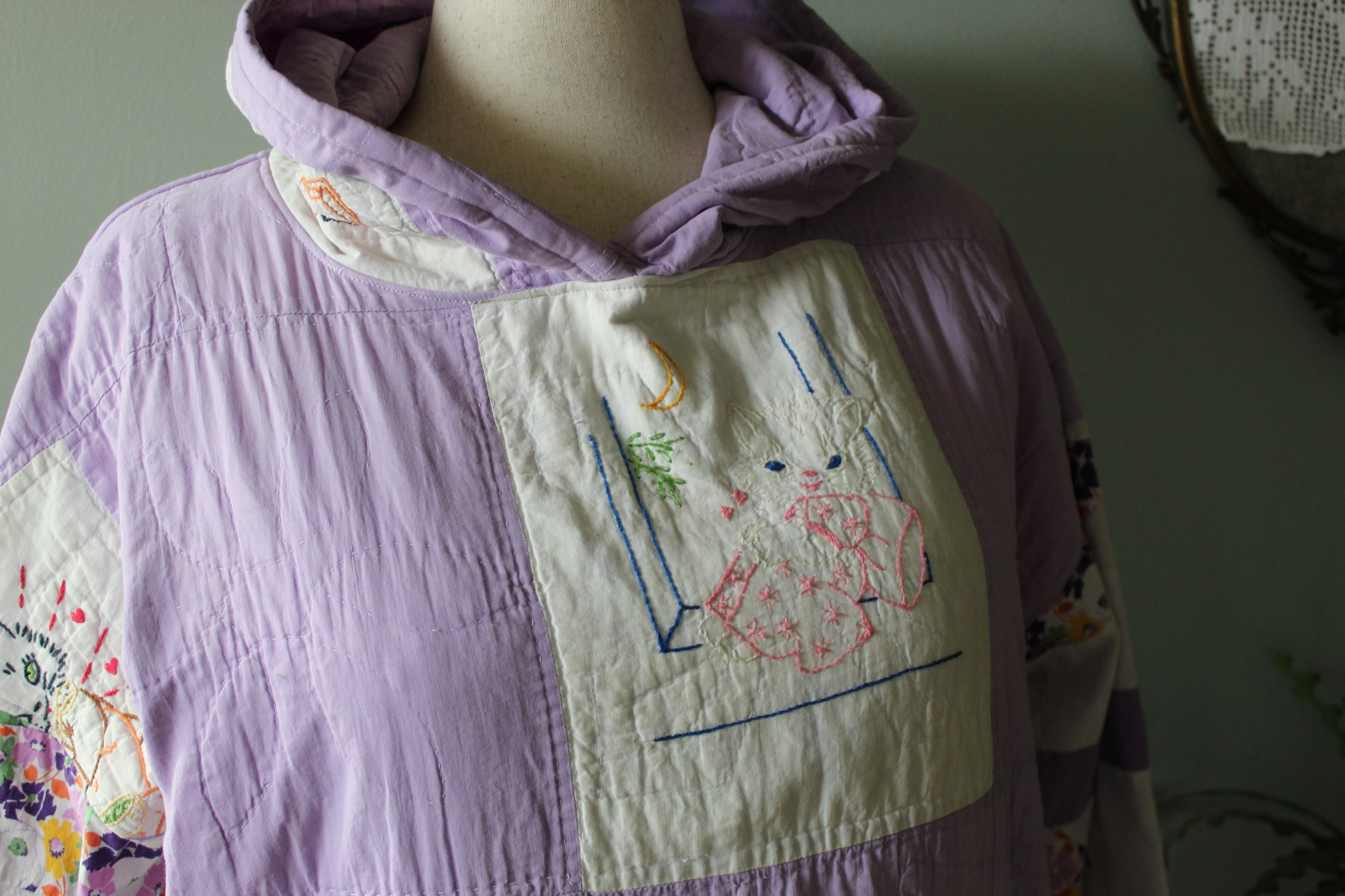 Mannequin wearing a quilted jacket with embroidered designs on a plain background