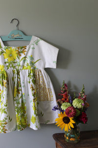 Floral-patterned tunic on a hanger with a bouquet of flowers on a gray surface