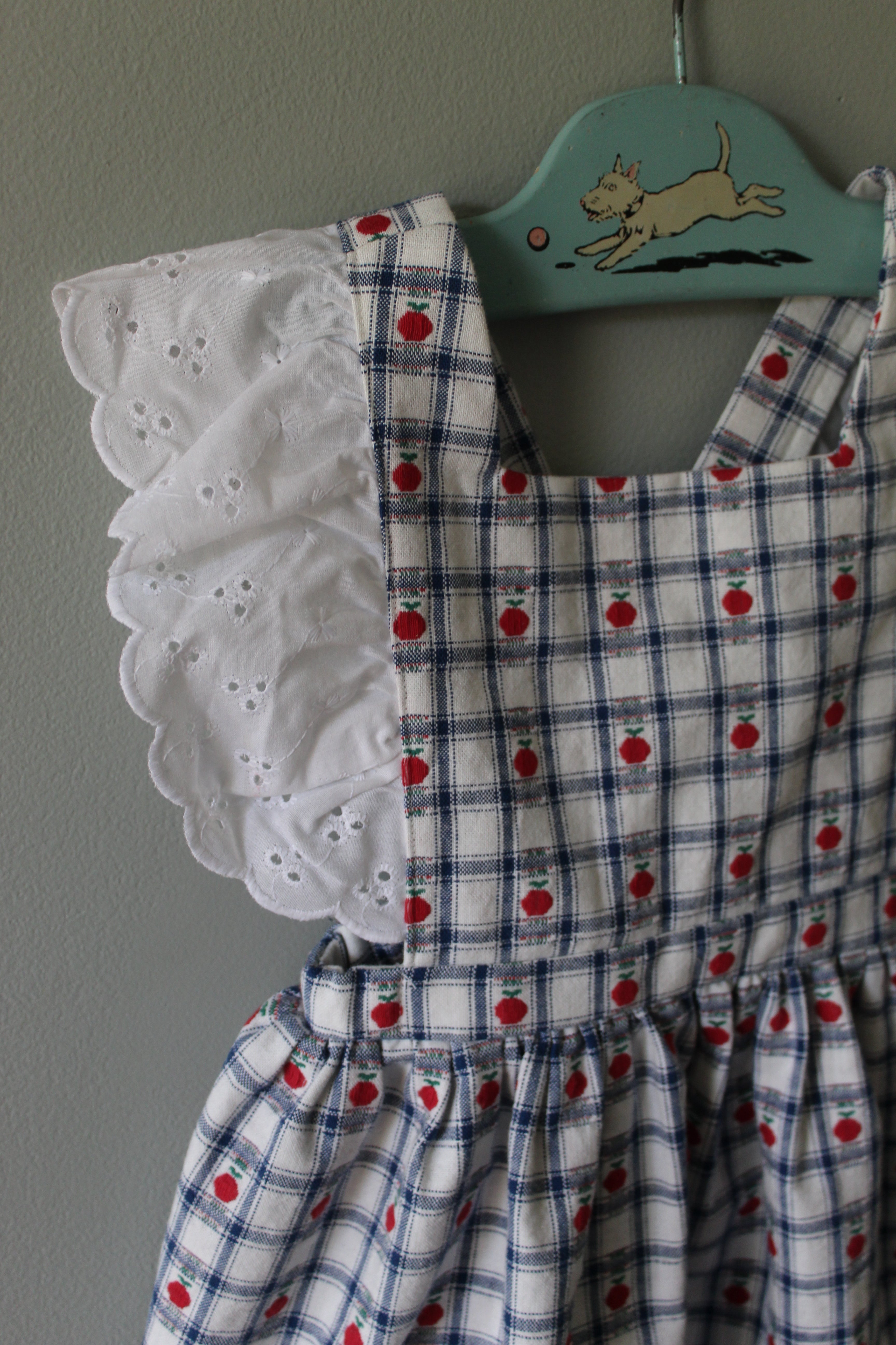Plaid dress with red polka dots and white lace trim on a gray background