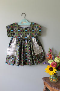 Floral-patterned tunic with calender pockets on a hanger against a plain background