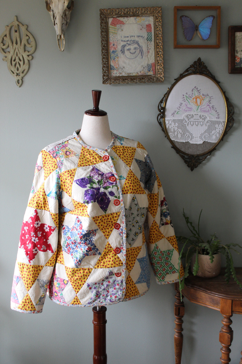 Quilted coat on a mannequin with decorative elements on a wall.