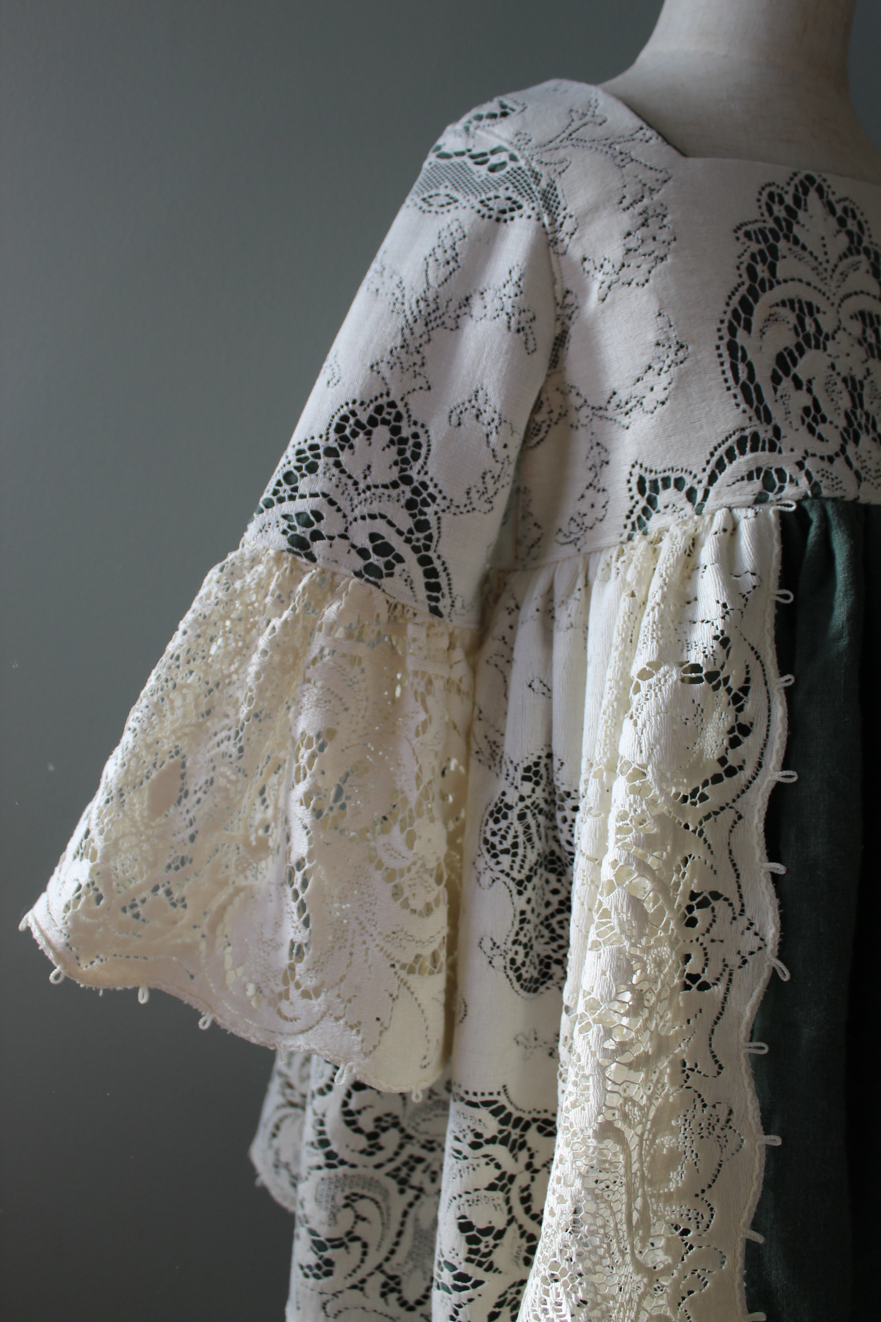 White lace fabric with green patterns on a gray background