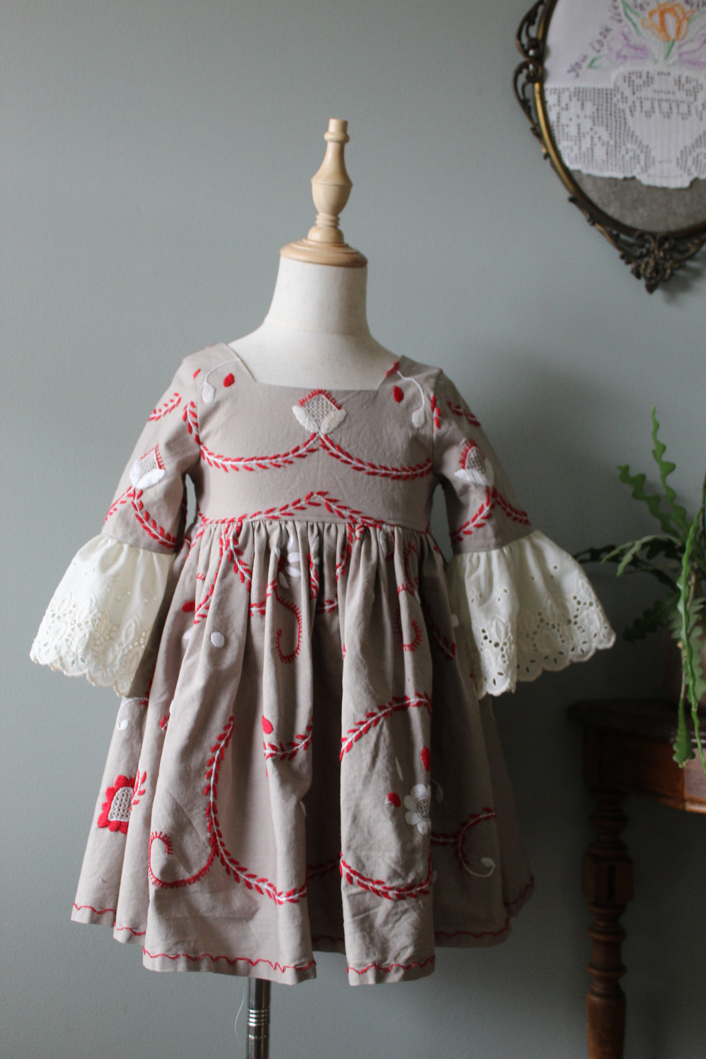 Embroidered scandinavian dress with heart patterns on a mannequin against a plain background