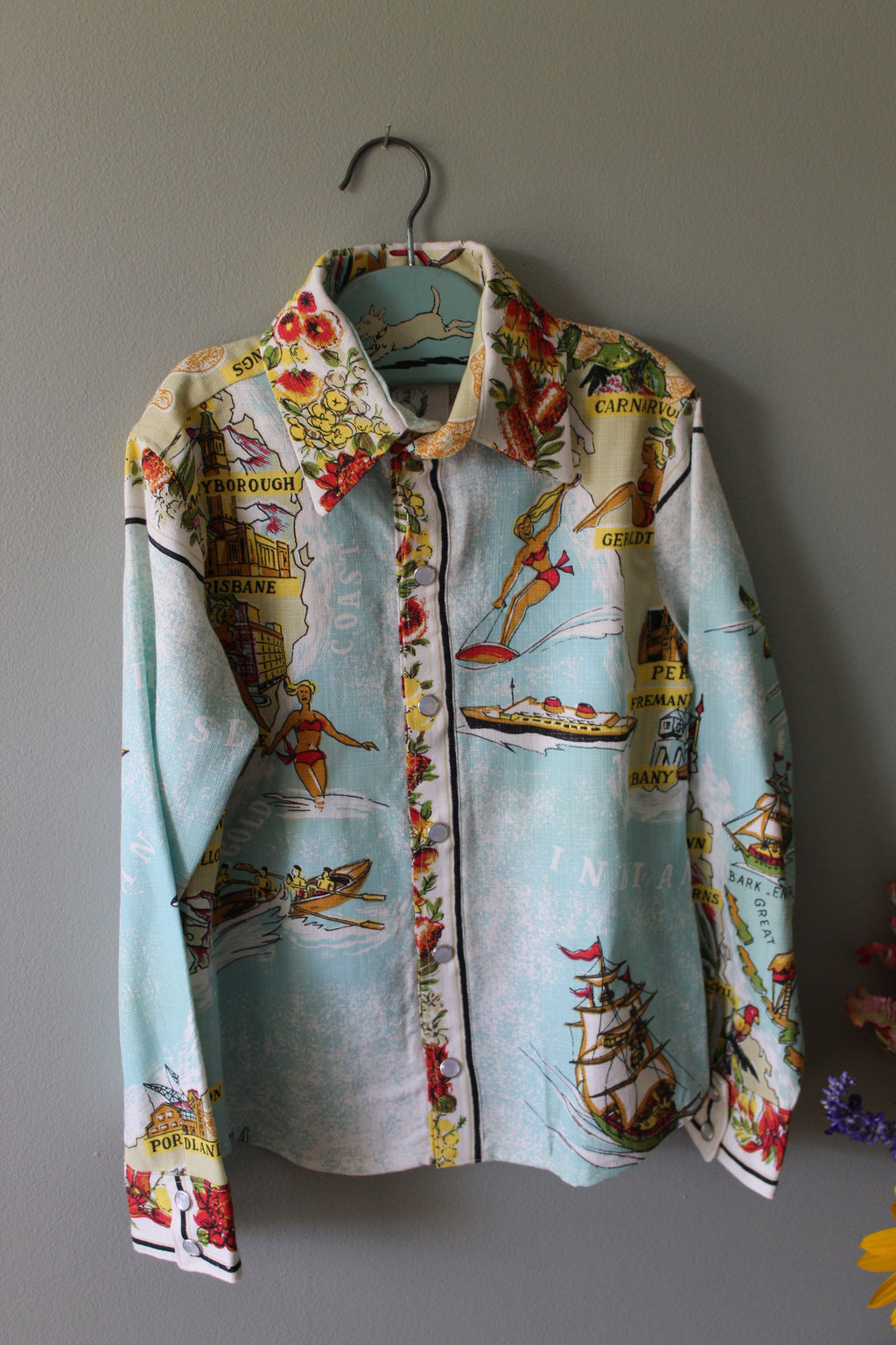 Vintage retro australia pearl snap kids shirt hanging on gray wall
