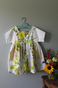 Floral-patterned shirt on a hanger against a gray background with a vase of flowers.
