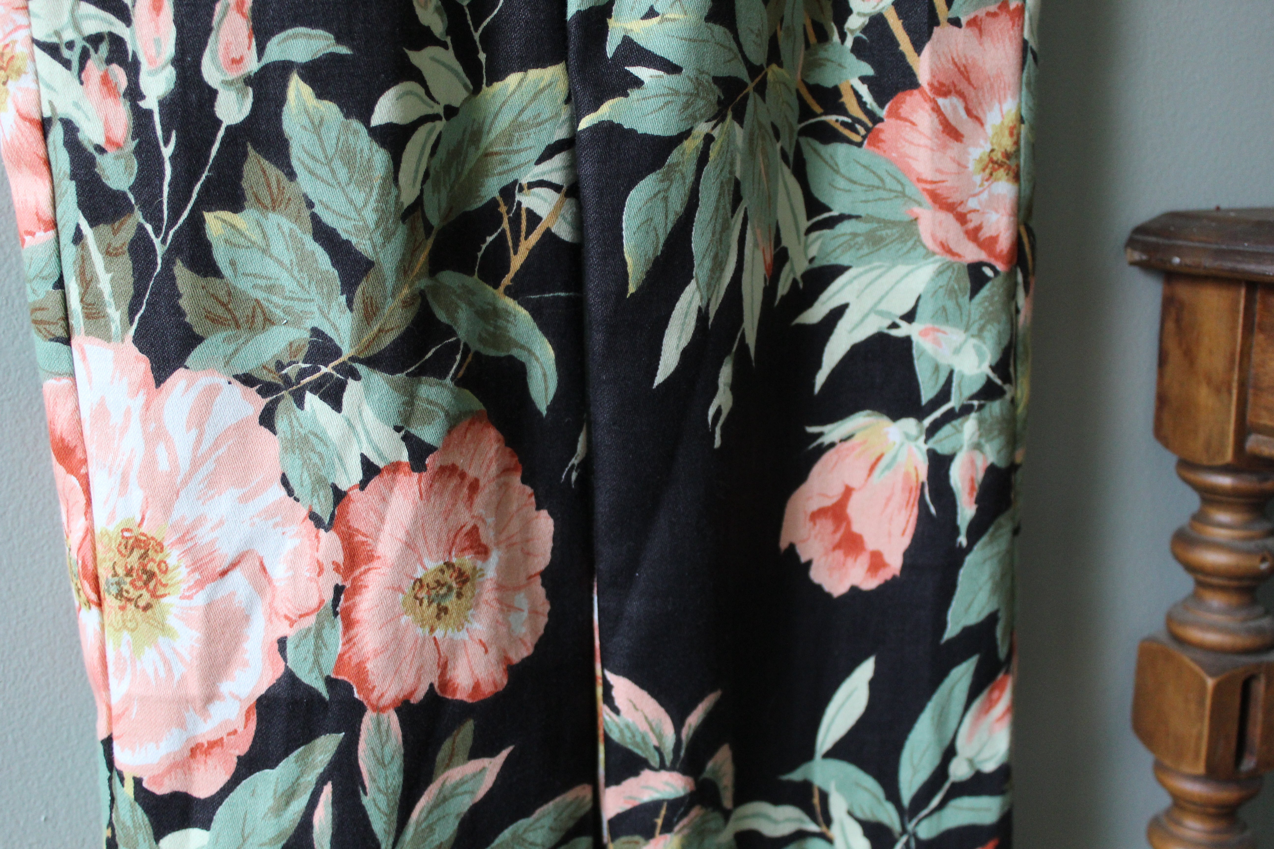 Floral patterned fabric with pink flowers and green leaves on a dark background.