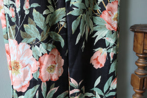 Floral patterned fabric with pink flowers and green leaves on a dark background.