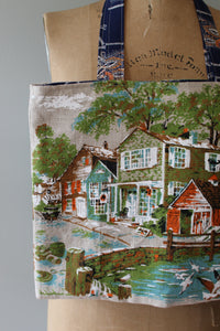 Fabric with a scenic print of houses and trees draped over a mannequin.