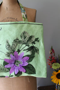 Green fabric with a purple flower design on a cardboard surface