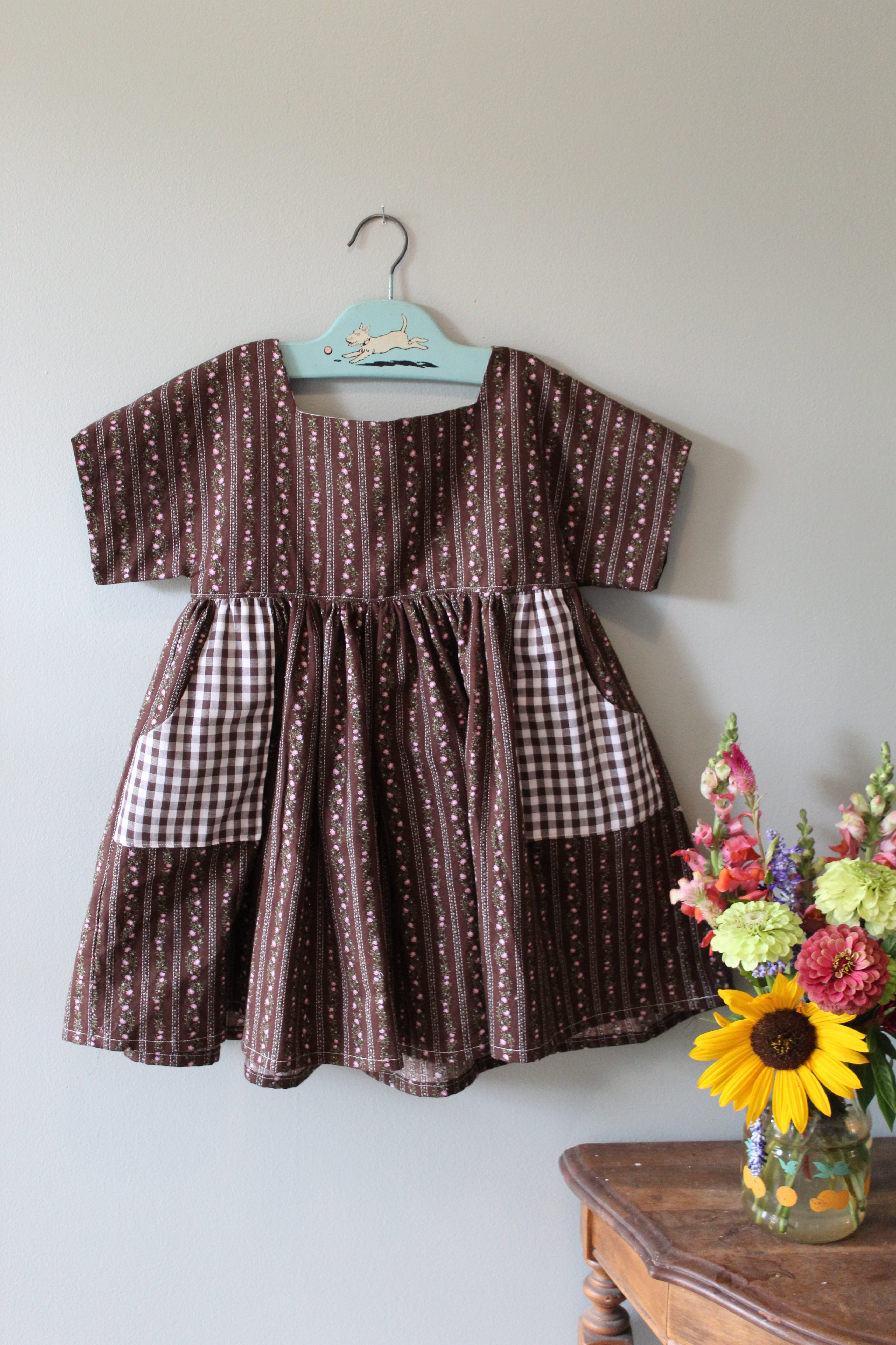 Patchwork tunic dress with brown and white pattern on a light gray background