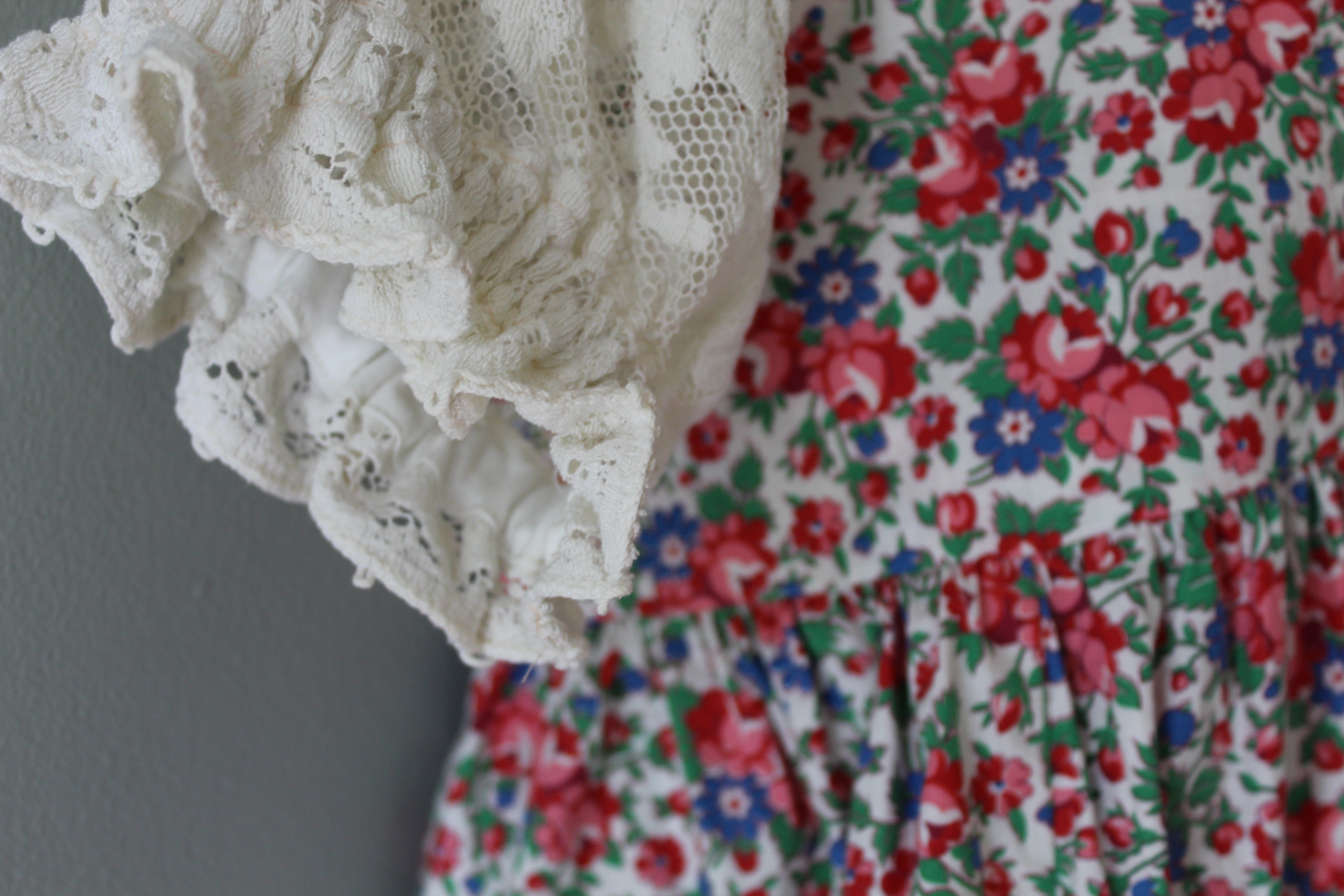 Close-up of a floral dress with lace details on a plain background