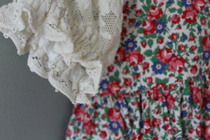 Close-up of a floral dress with lace details on a plain background