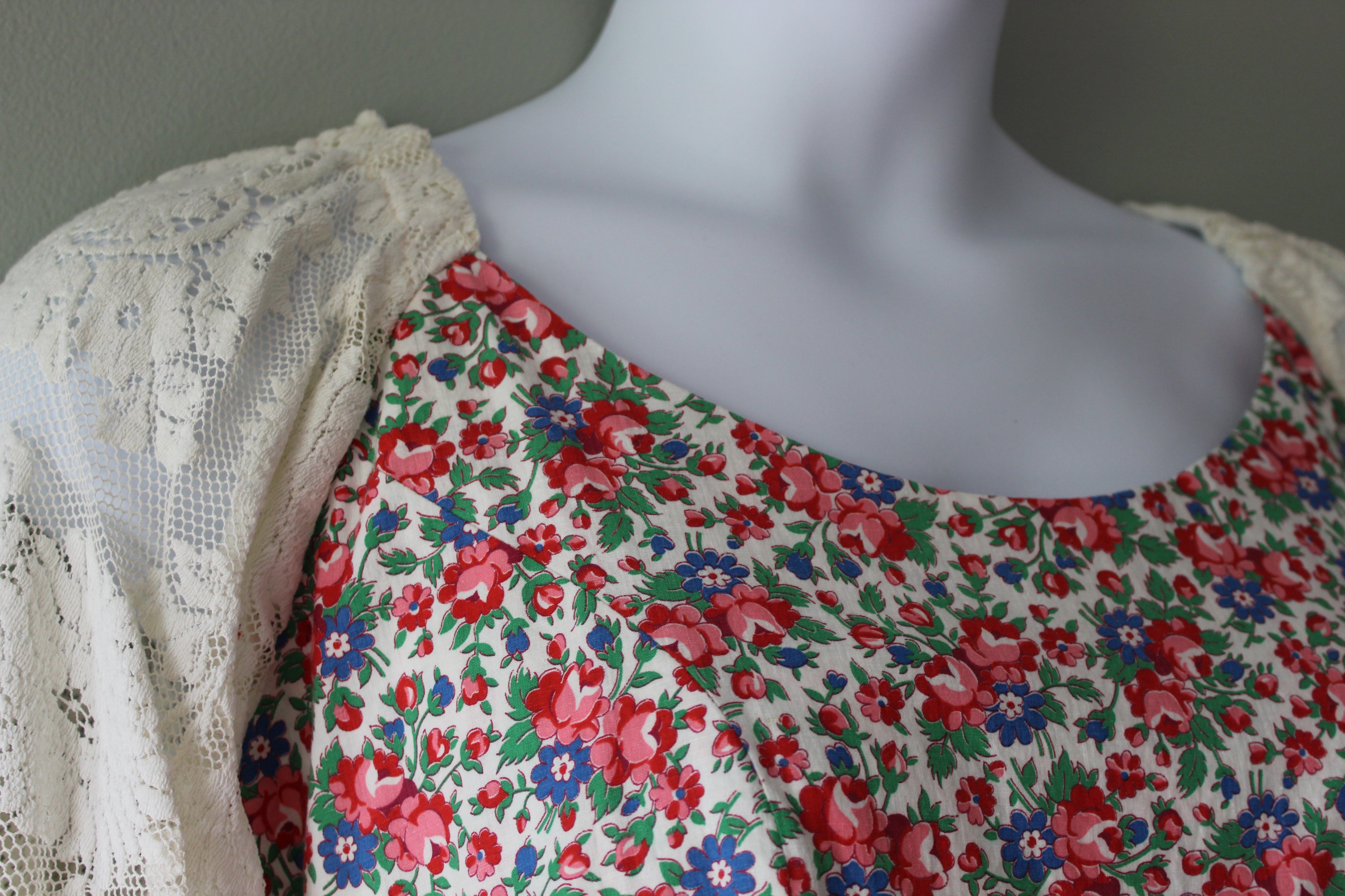 Mannequin wearing a floral dress with a lace overlay against a neutral background