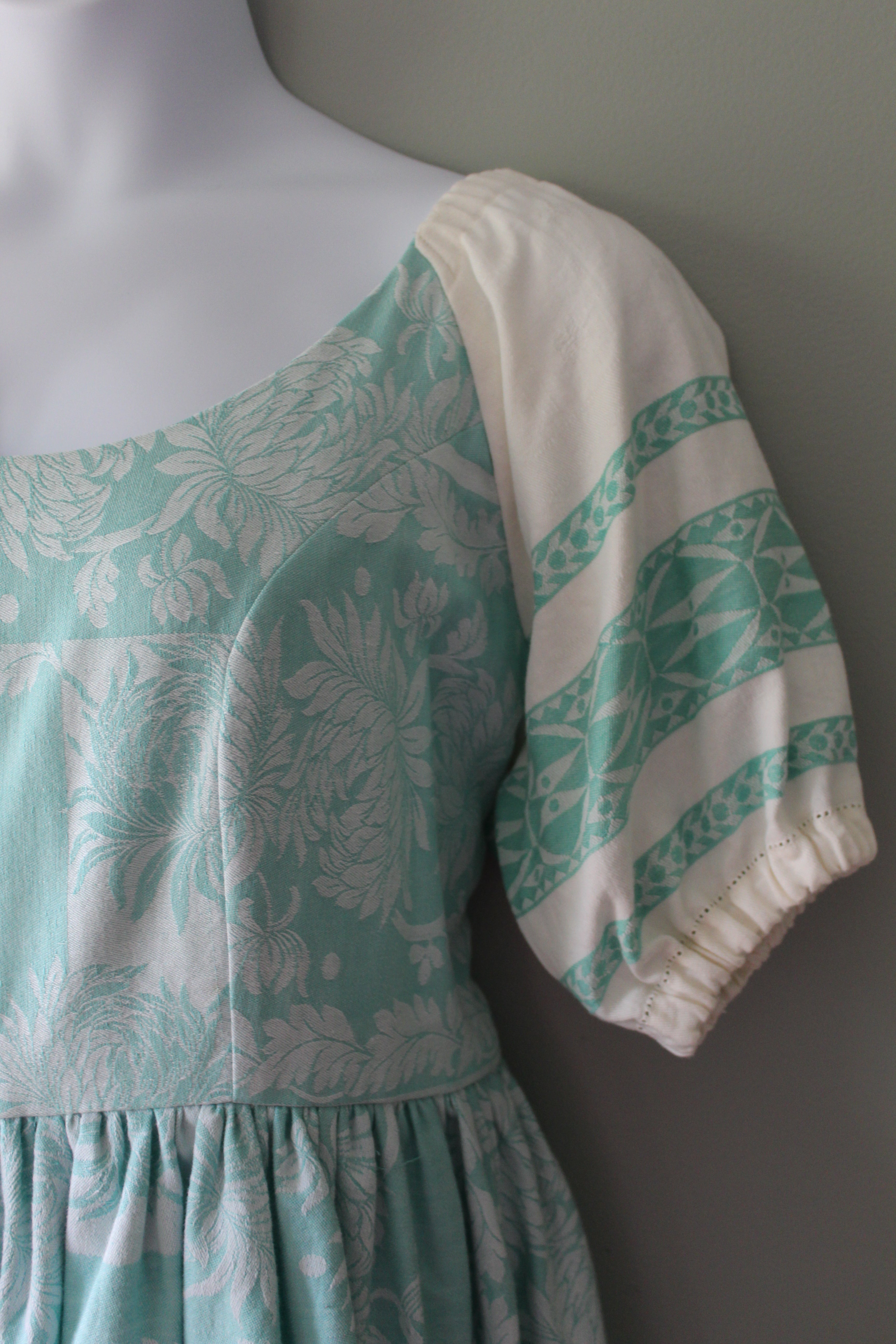 Teal and white floral patterned linen dress on a gray surface