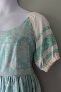 Teal and white floral patterned linen dress on a gray surface