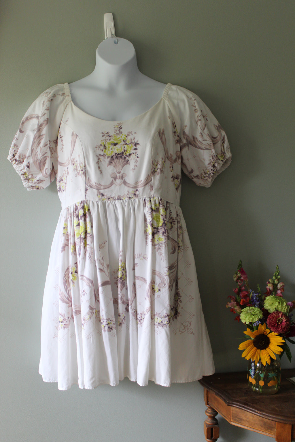 White dress with floral patterns on a mannequin against a plain background