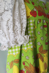 Green fabric blouse with strawberry patterns and a white lace sleeves.