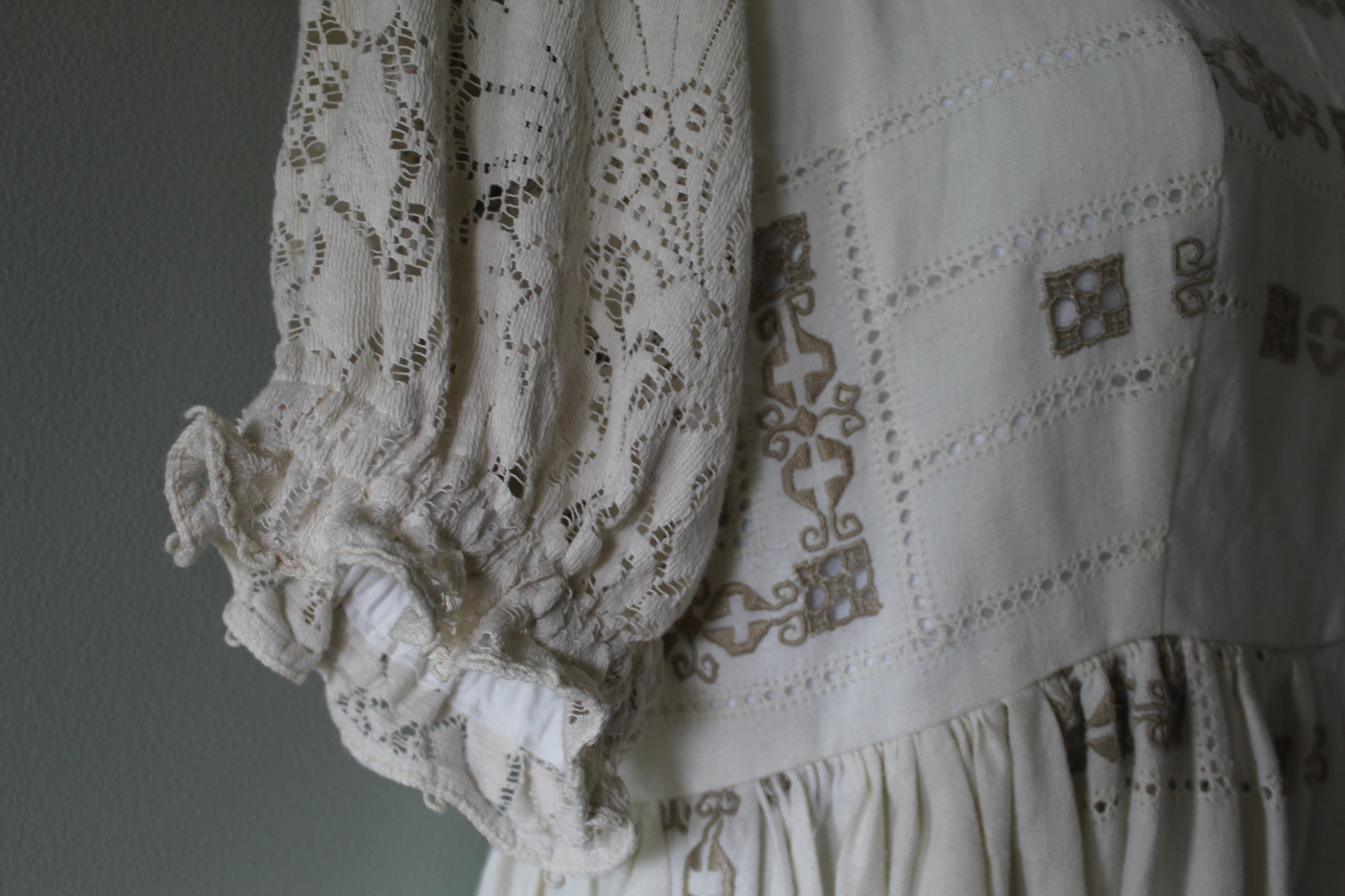 Close-up of a white lace garment with intricate patterns on a plain background